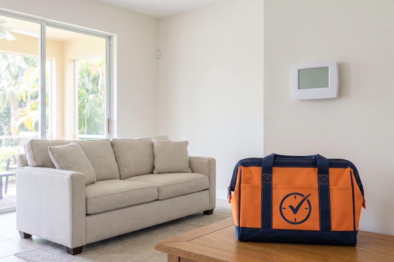 Bright living room with a wall thermostat and an HVAC tool bag