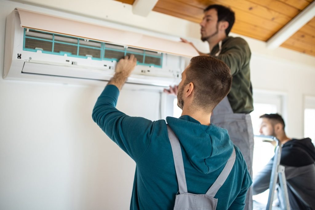 Technicians servicing a ductless AC system