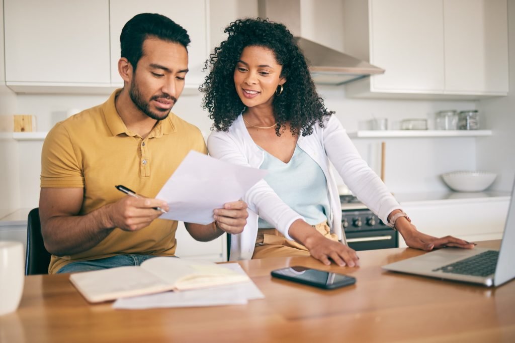 Two people reviewing paperwork at a kitchen counter